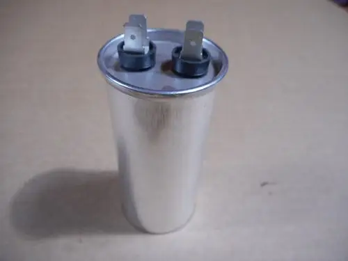 Aluminiumbedampfter Kondensator mit zwei Anschlüssen, verwendet in Heizsystemen von Remeha. Das Gehäuse ist zylindrisch und metallisch glänzend.